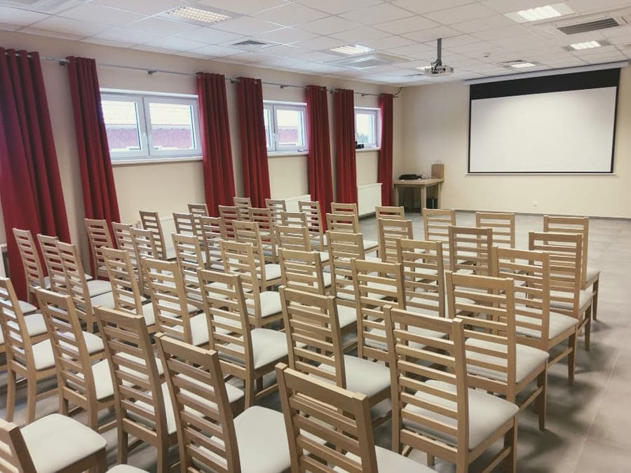 Klimatyzowana sala konferencyjna w ustawieniu teatralnym, z ekranem i rzutnikiem